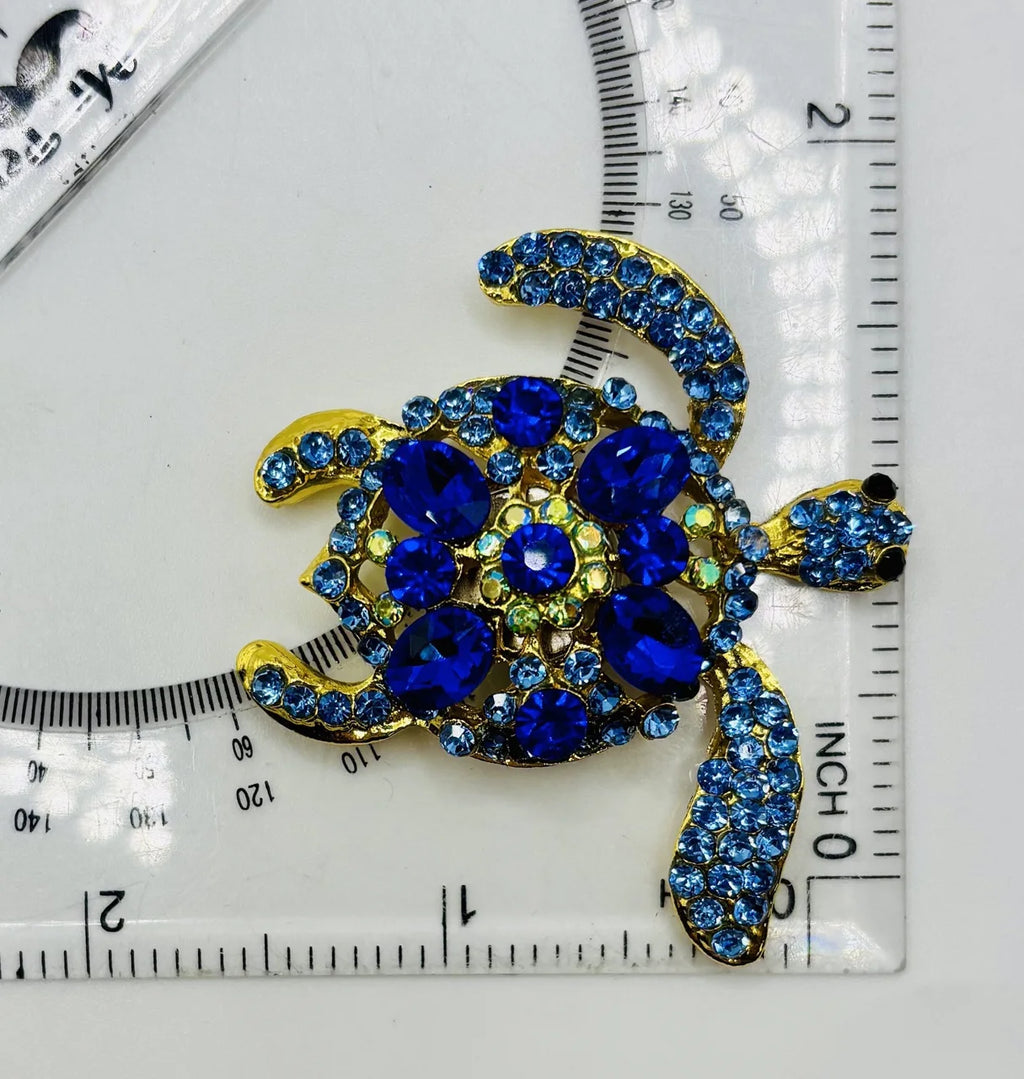 Blue sea turtle needle minder beside a ruler for scale
