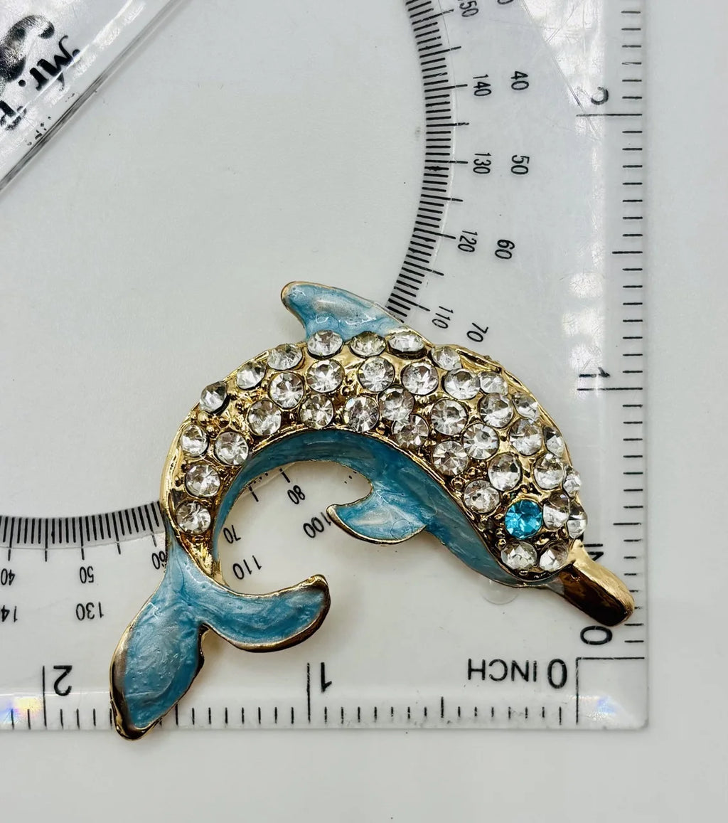 Blue crystal dolphin needle minder beside a ruler for scale