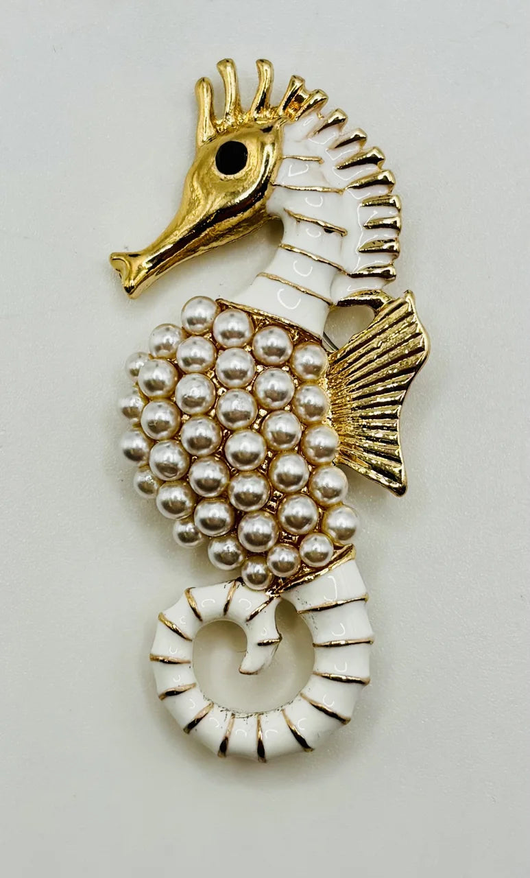 Gold and pearl seahorse needle minder on a white background
