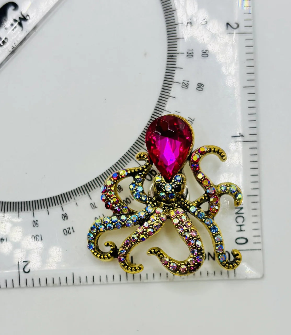 Pink crystal octopus needle minder beside a ruler for scale