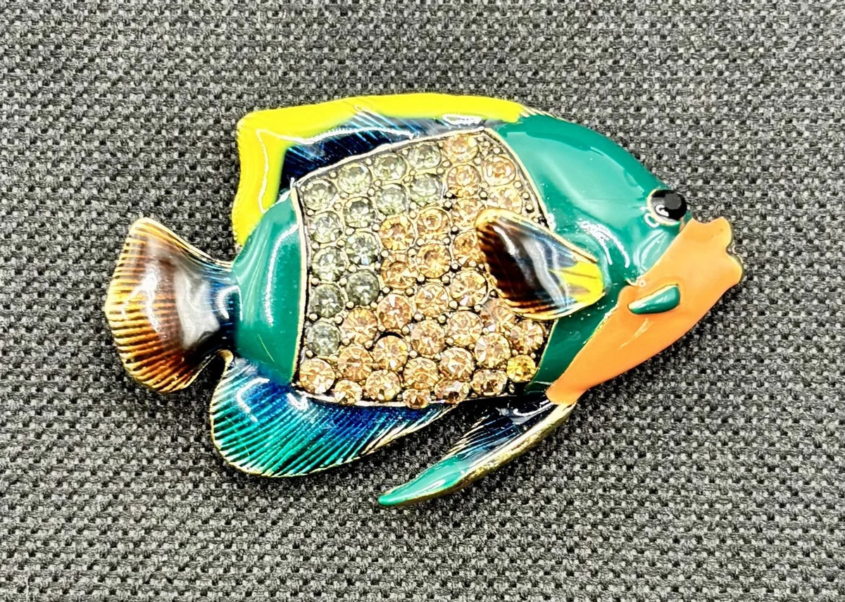 Colorful enamel and crystal tropical fish needle minder on dark fabric