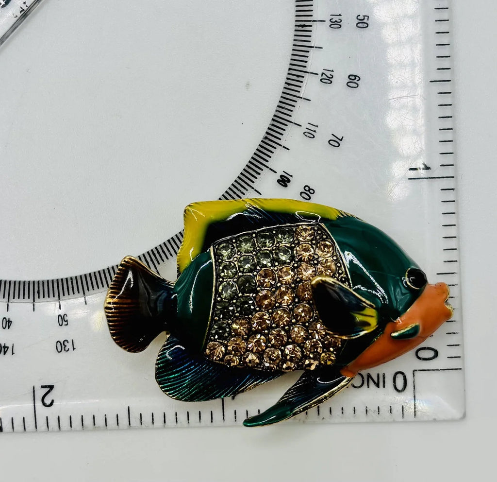 Colorful enamel and crystal tropical fish needle minder beside a ruler for scale