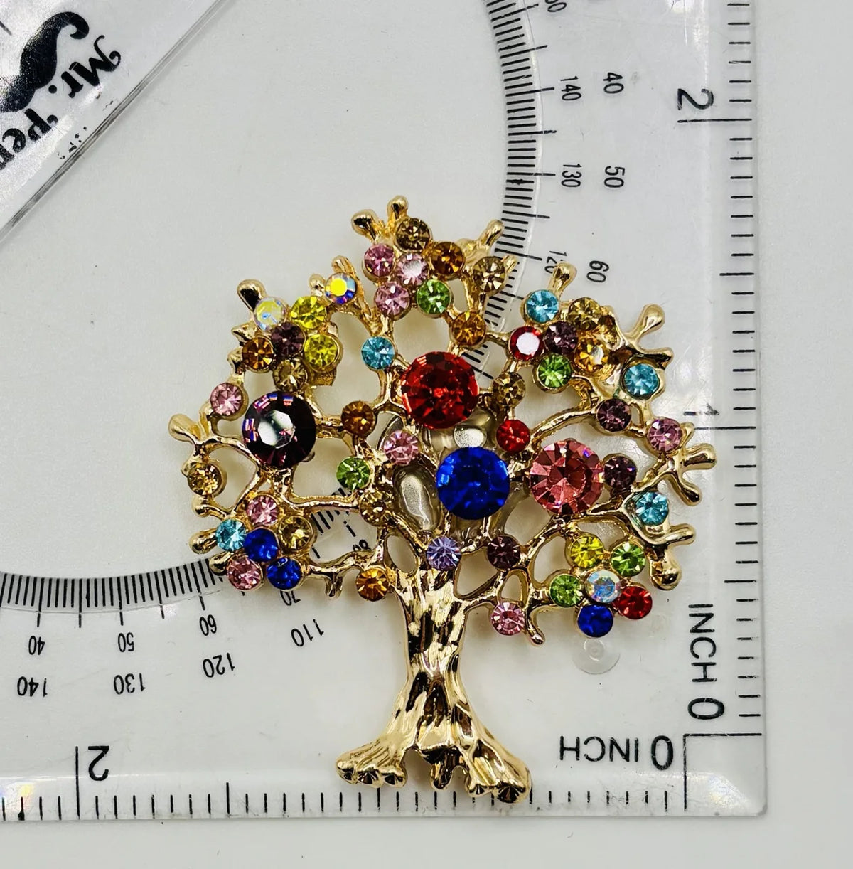 Colorful tree of life needle minder beside a ruler for scale