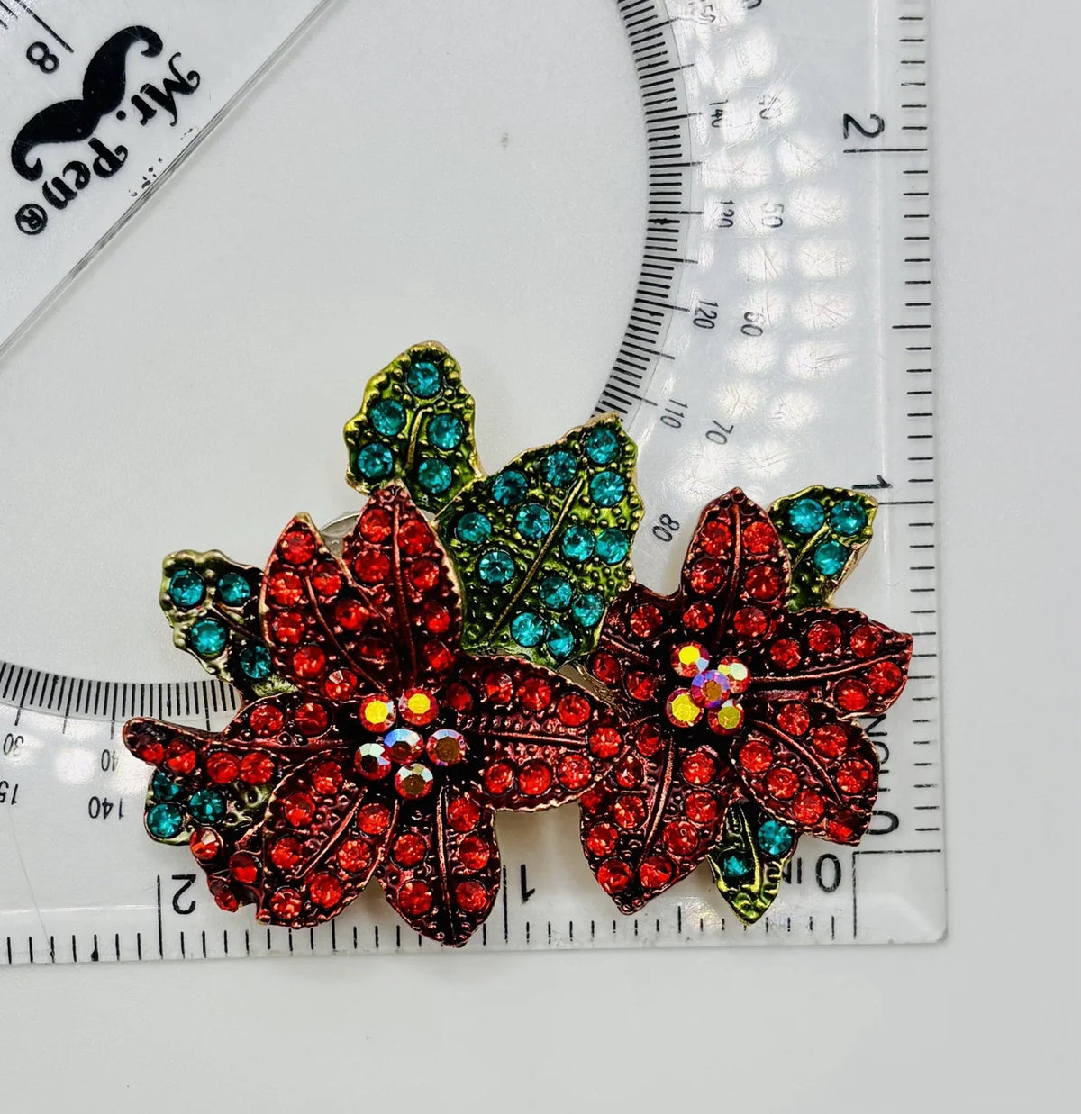 Crystal red poinsettia needle minder beside a ruler for scale