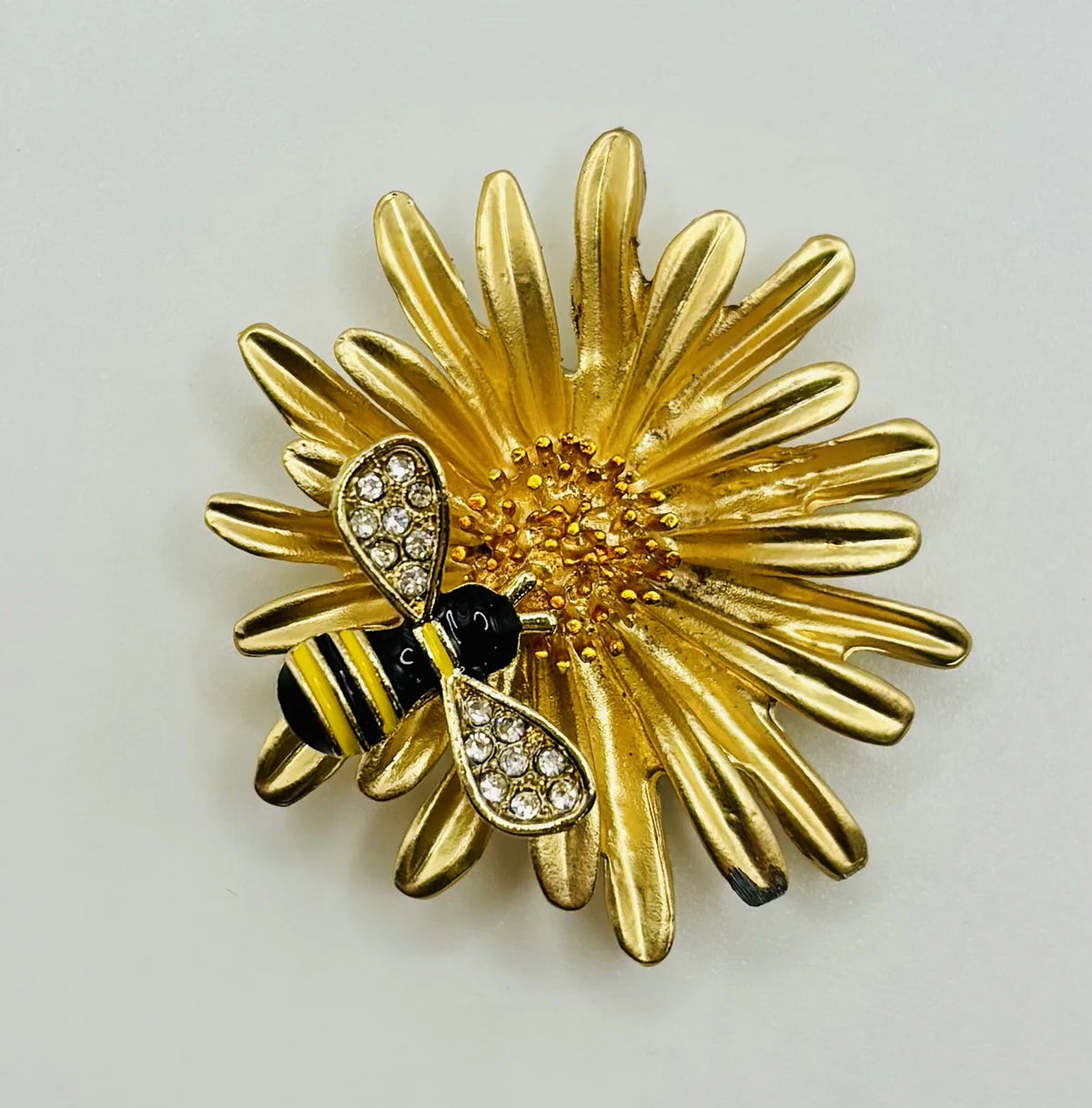 Enamel daisy with bee needle minder on a white background