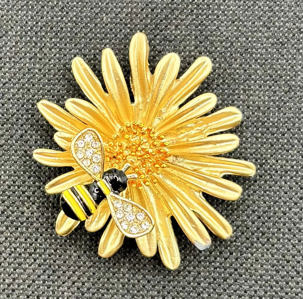 Enamel daisy with bee needle minder on dark fabric