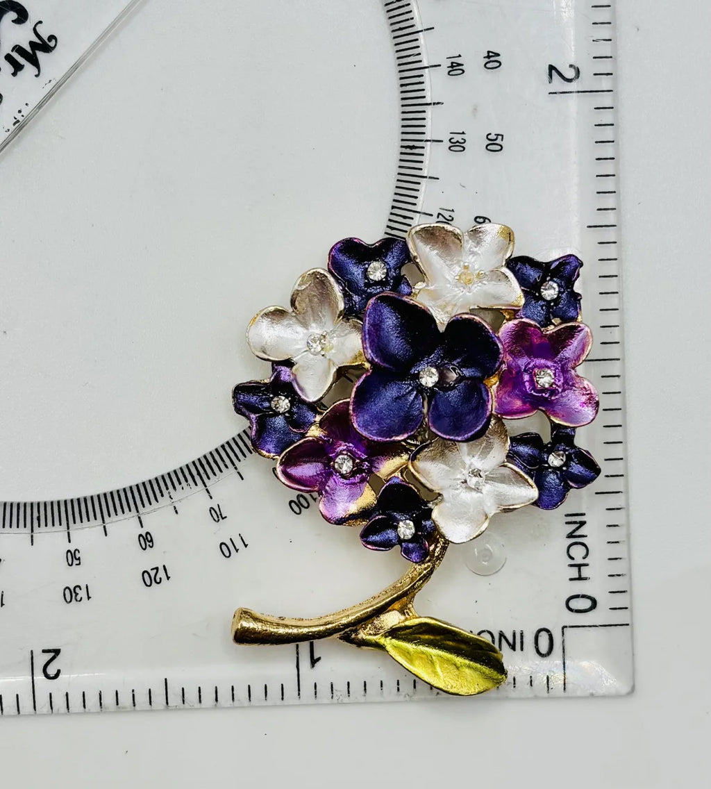 Purple enamel hydrangea needle minder beside a ruler for scale