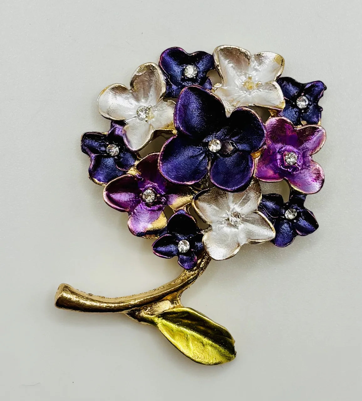Purple enamel hydrangea needle minder on a white background