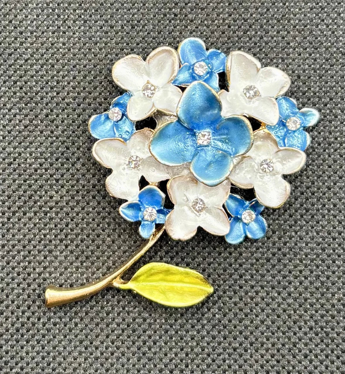 Blue and white enamel needle minder on dark fabric