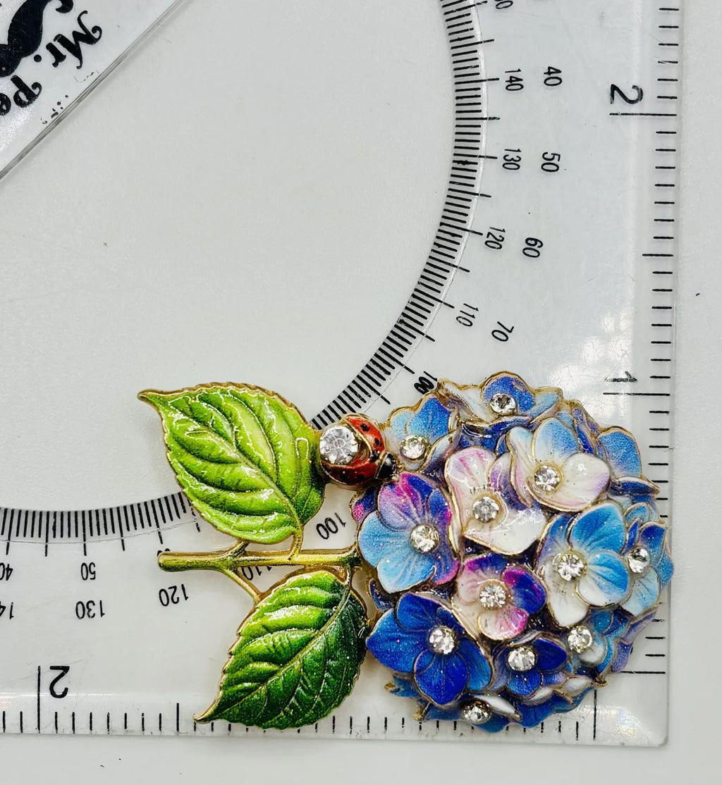 Blue and lavender hydrangea needle minder beside a ruler for scale