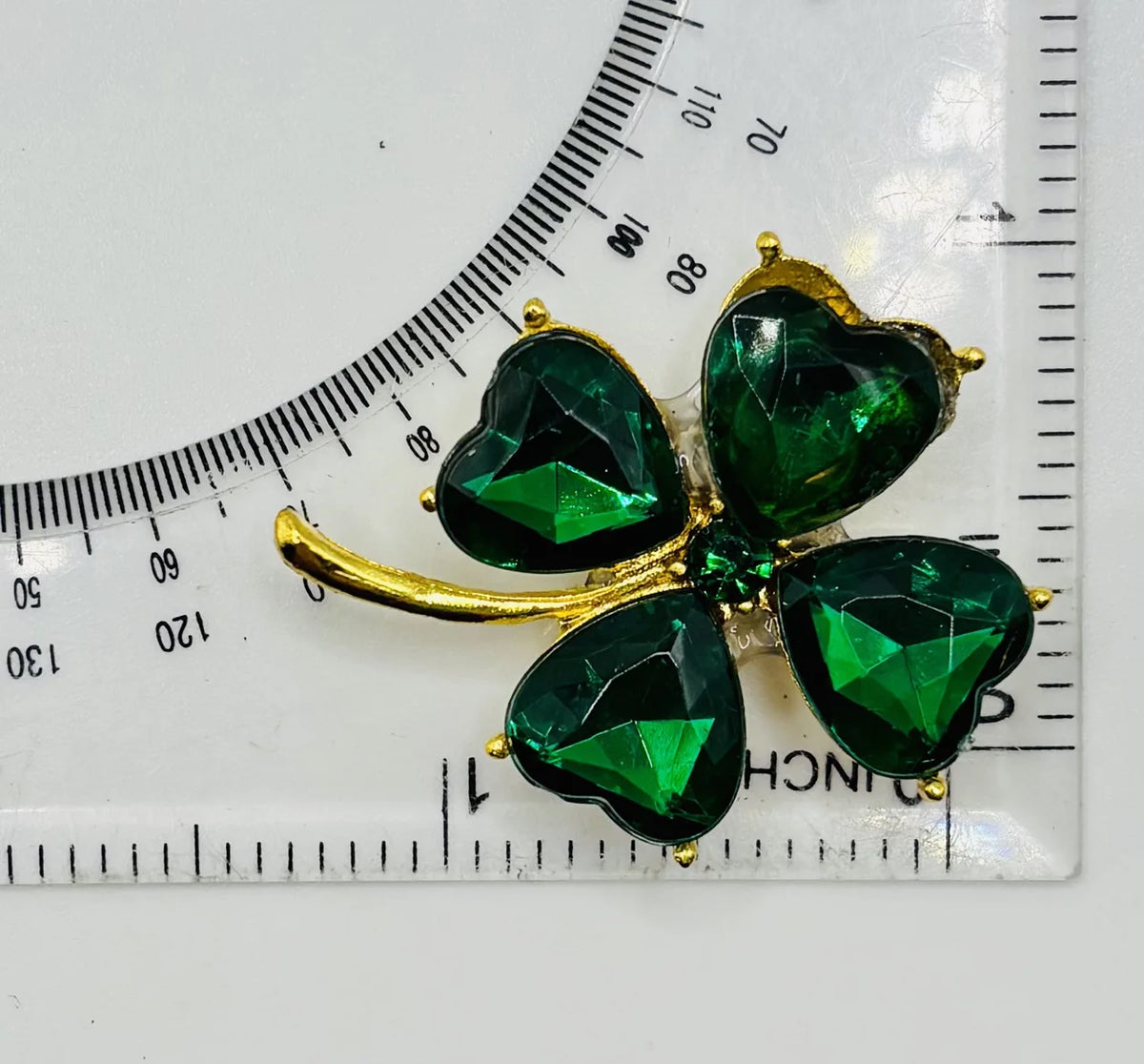 Small crystal shamrock needle minder beside a ruler for scale