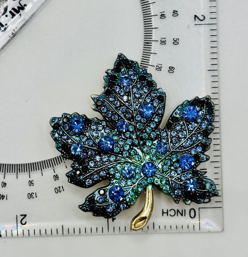 Blue crystal leaf needle minder beside a ruler for scale