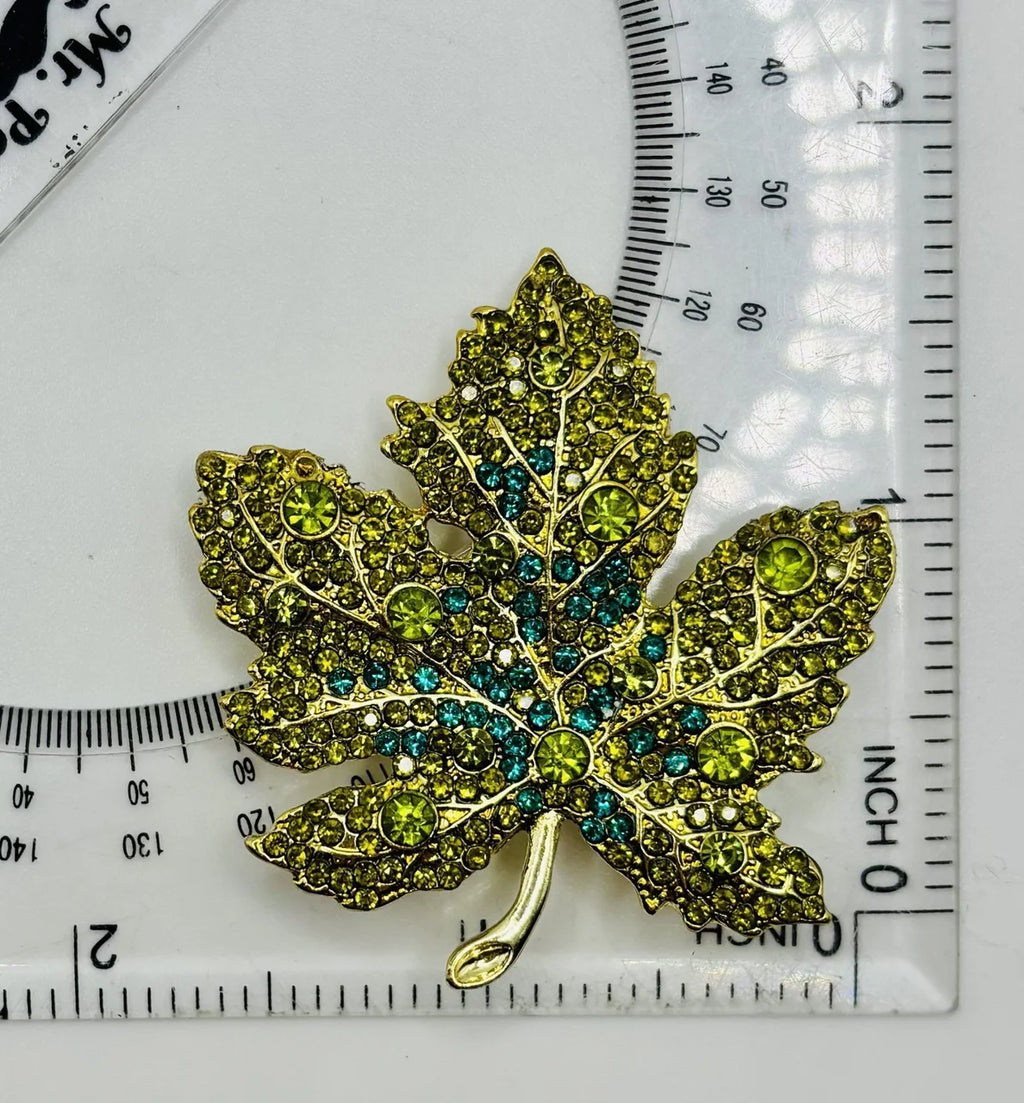 Green crystal leaf needle minder beside a ruler for scale