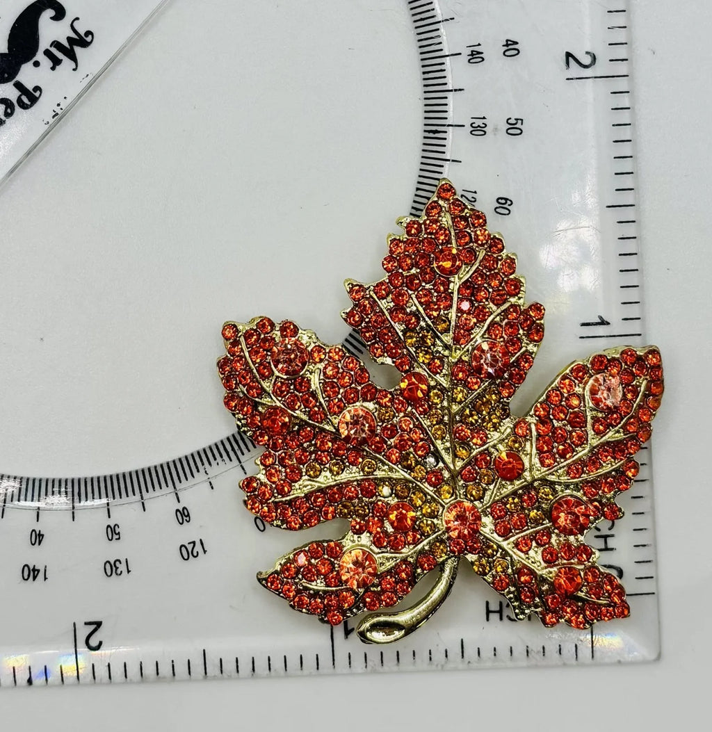 Orange crystal leaf needle minder beside a ruler for scale