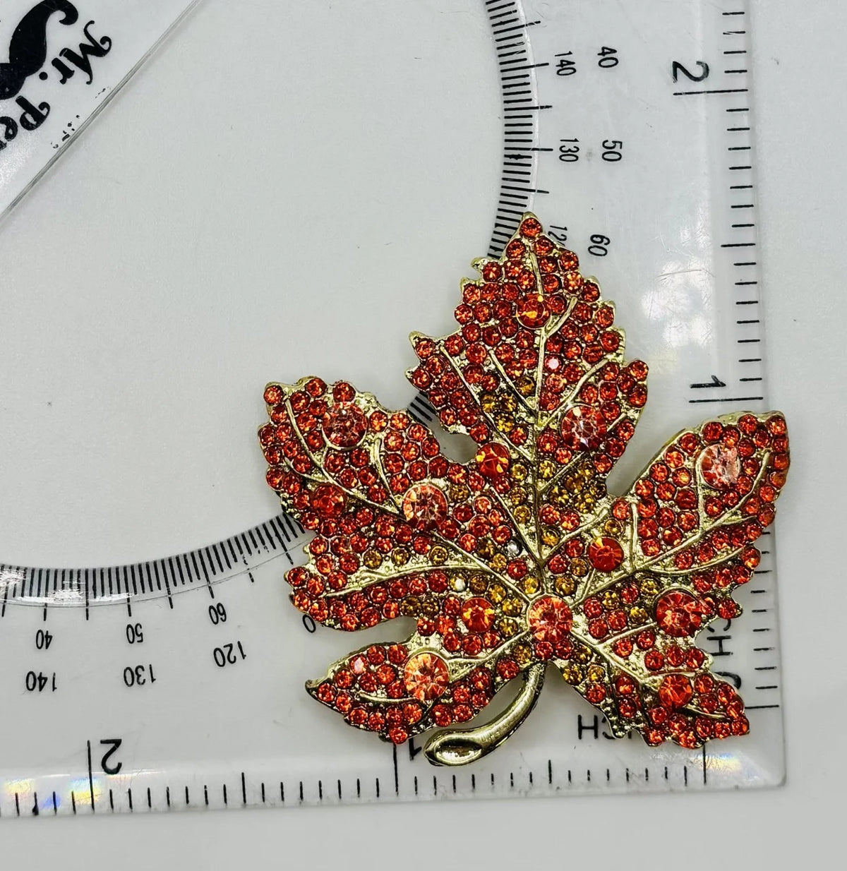 Orange crystal leaf needle minder beside a ruler for scale
