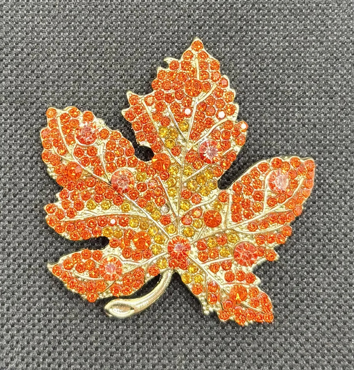 Orange crystal leaf needle minder on dark fabric