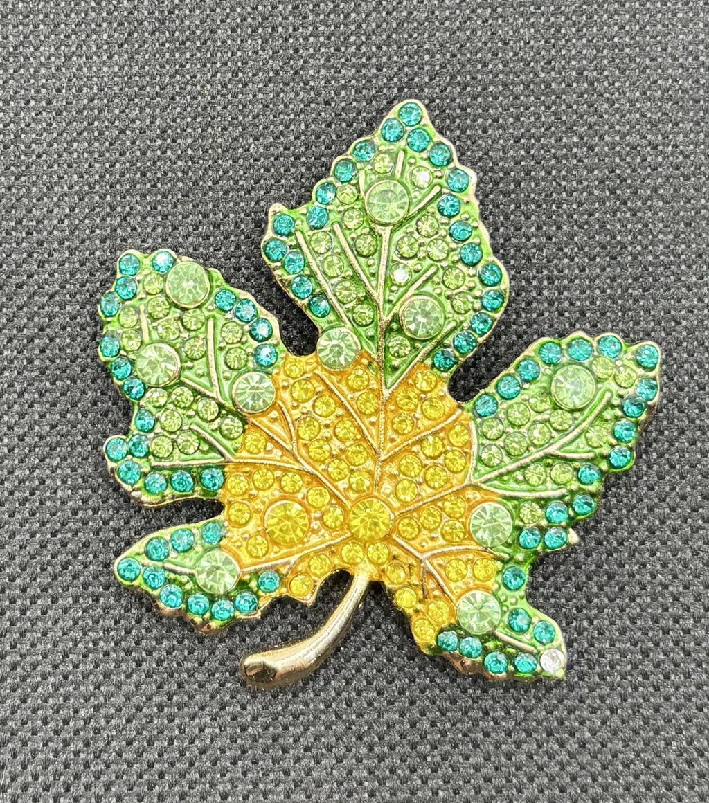 Green and yellow crystal leaf needle minder on dark fabric