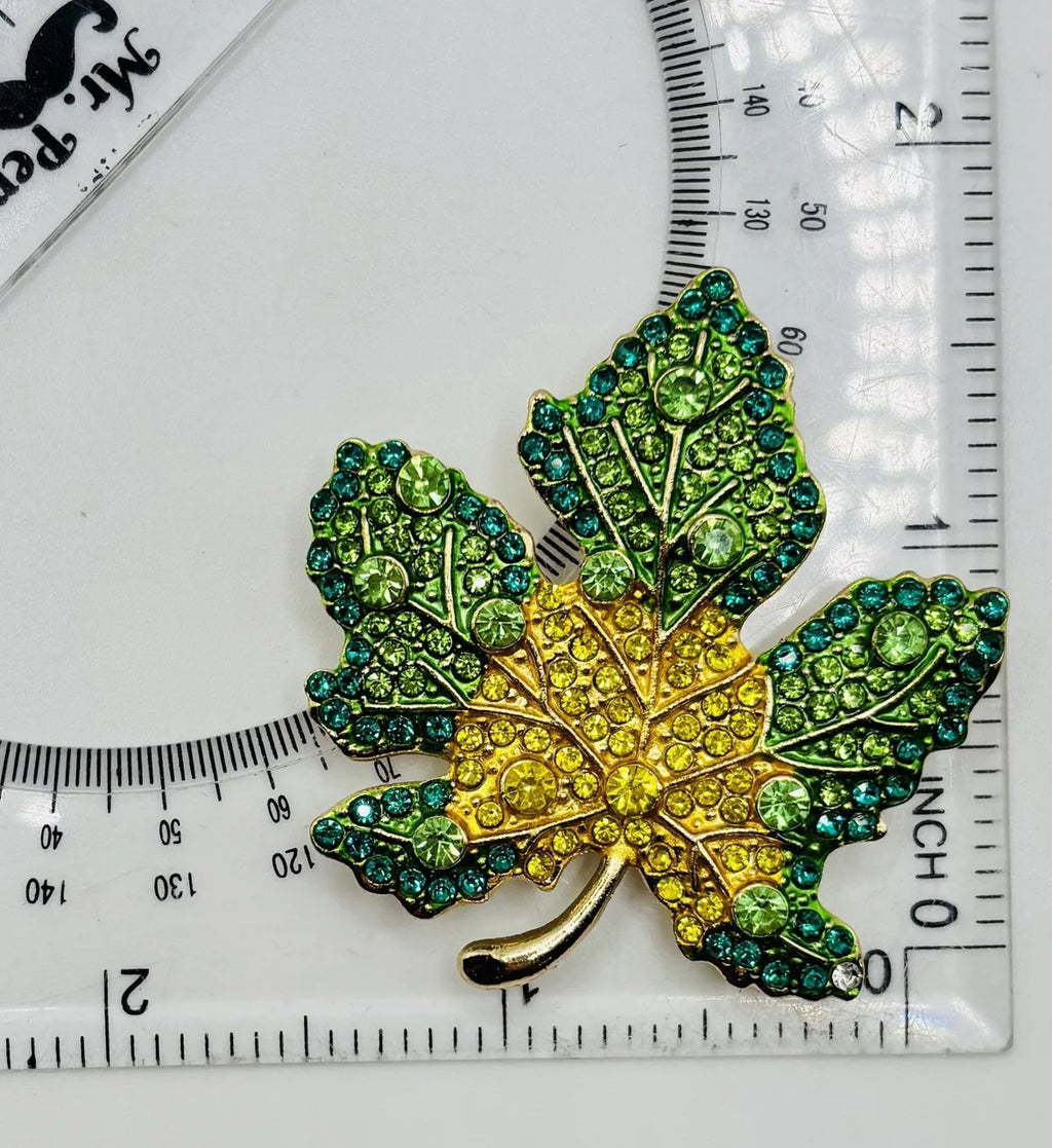 Green and yellow crystal leaf needle minder beside a ruler for scale