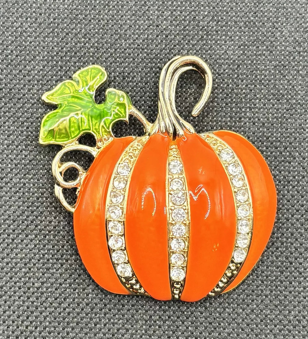 Large enamel pumpkin with crystals needle minder on dark fabric