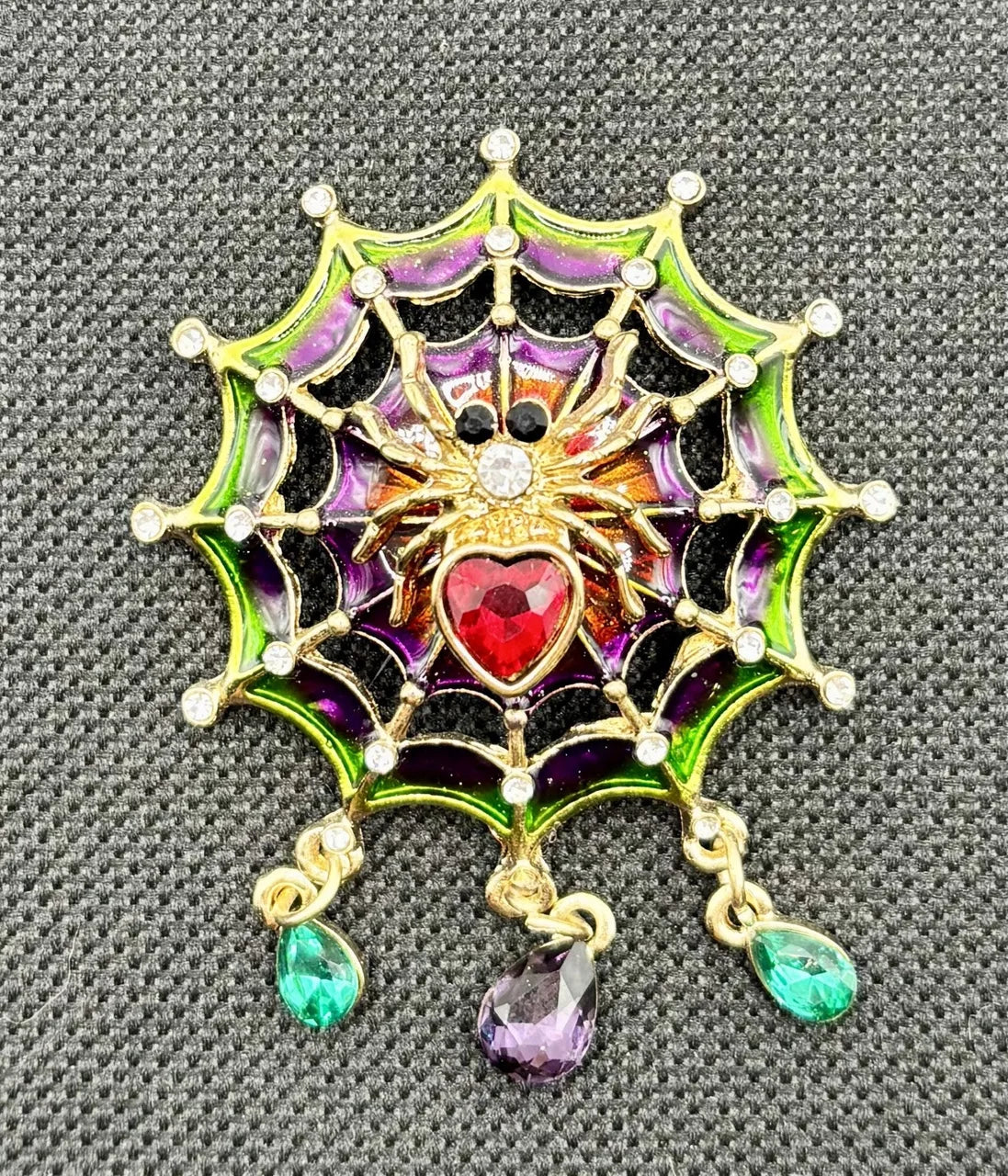 Jeweled spider in web needle minder on dark fabric