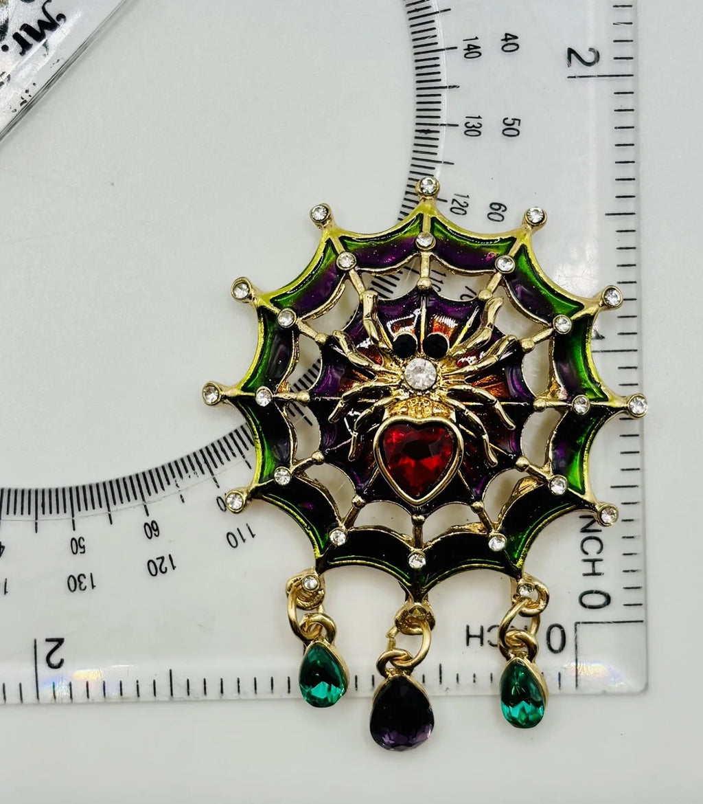 Jeweled spider in web needle minder beside a ruler for scale