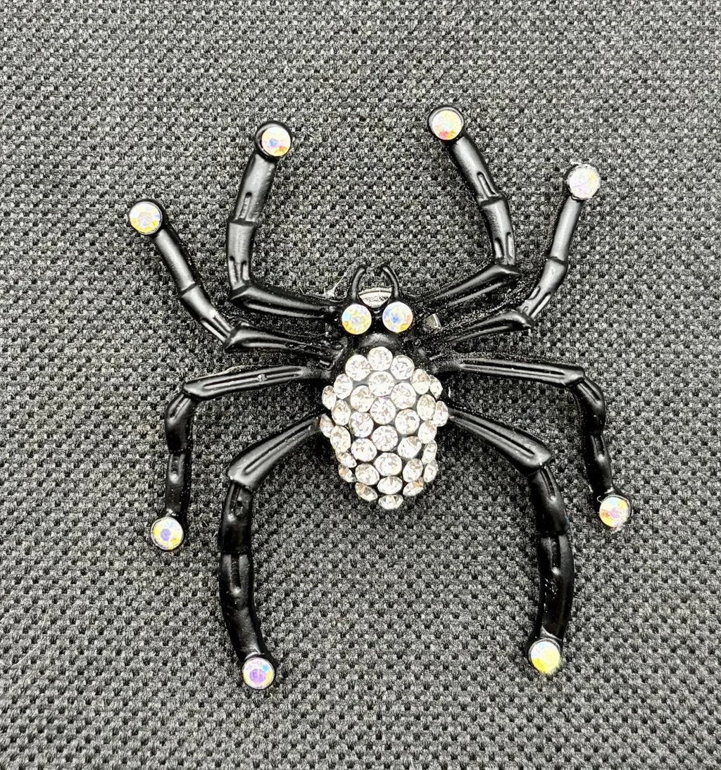 Black spider with crystals needle minder on dark fabric
