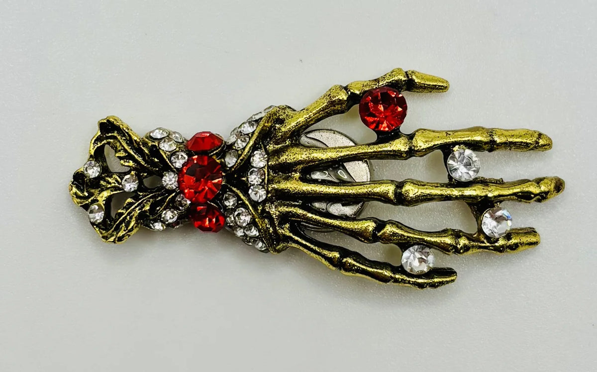 Gold and crystal skeleton hand needle minder on a white background