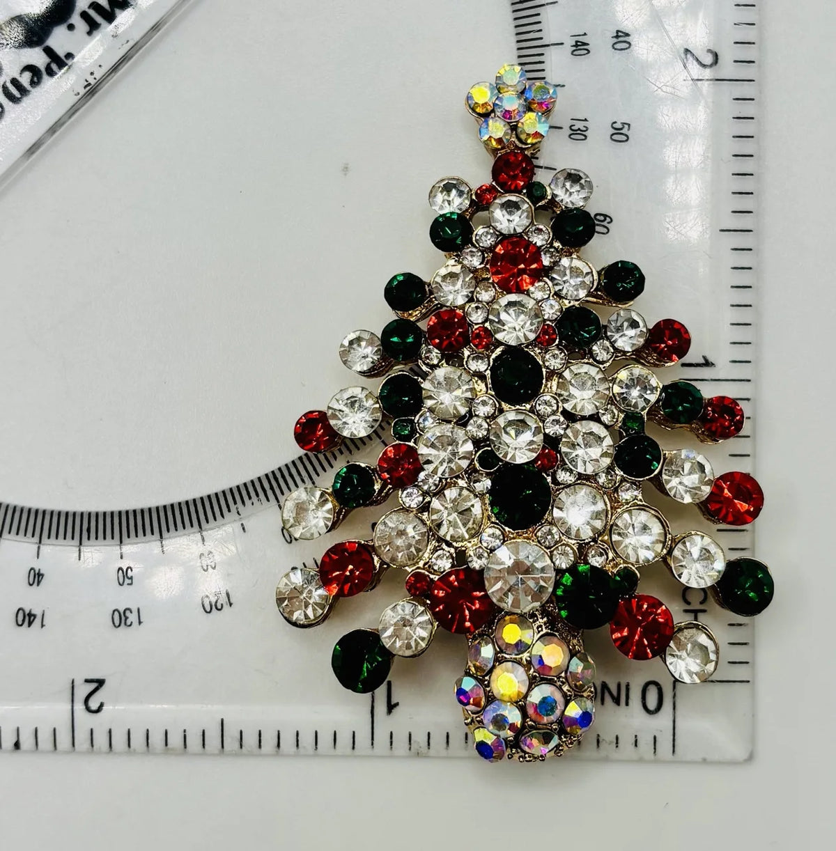 Crystal encrusted tree needle minder beside a ruler for scale