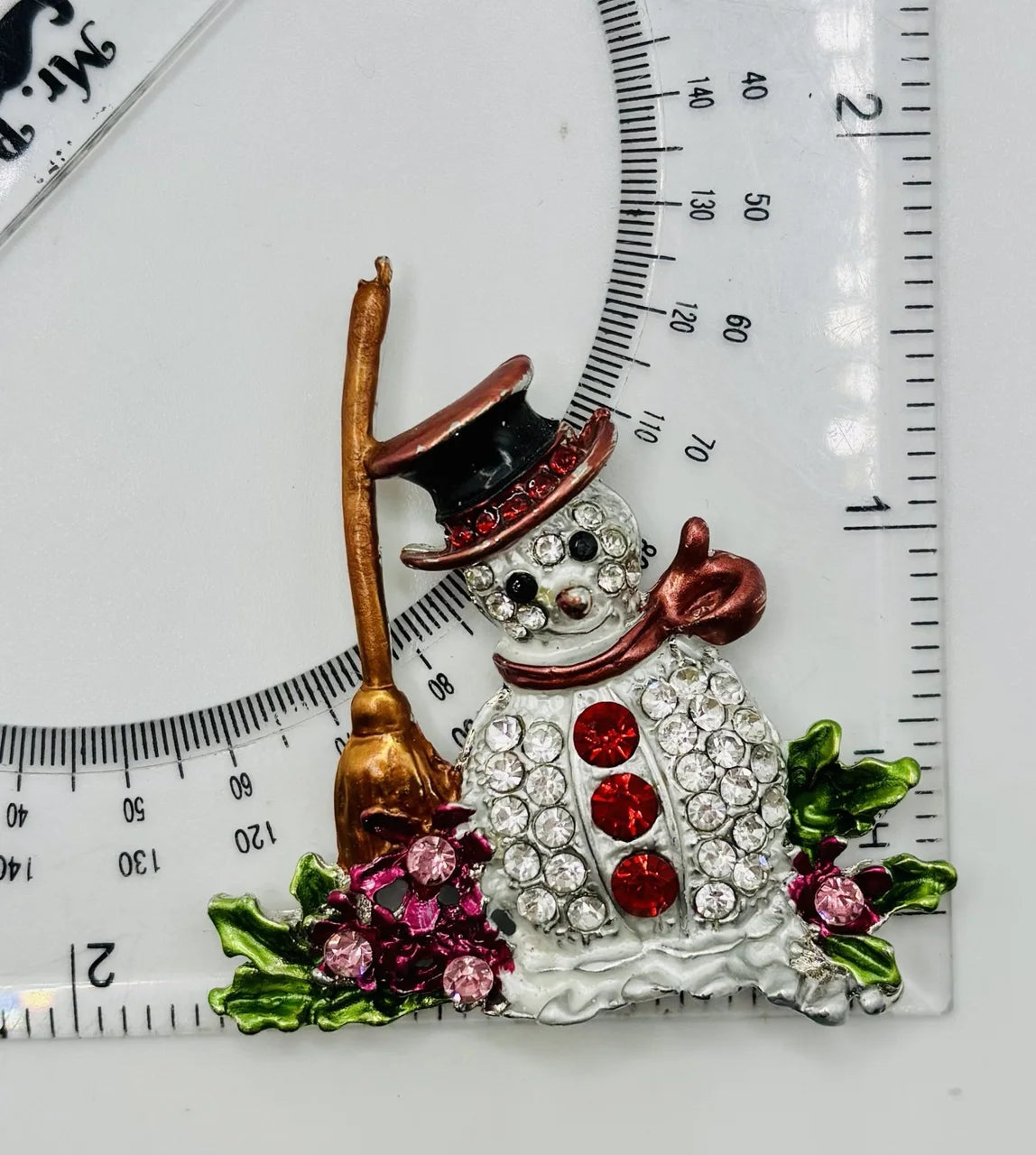 Snowman with broom needle minder beside a ruler for scale