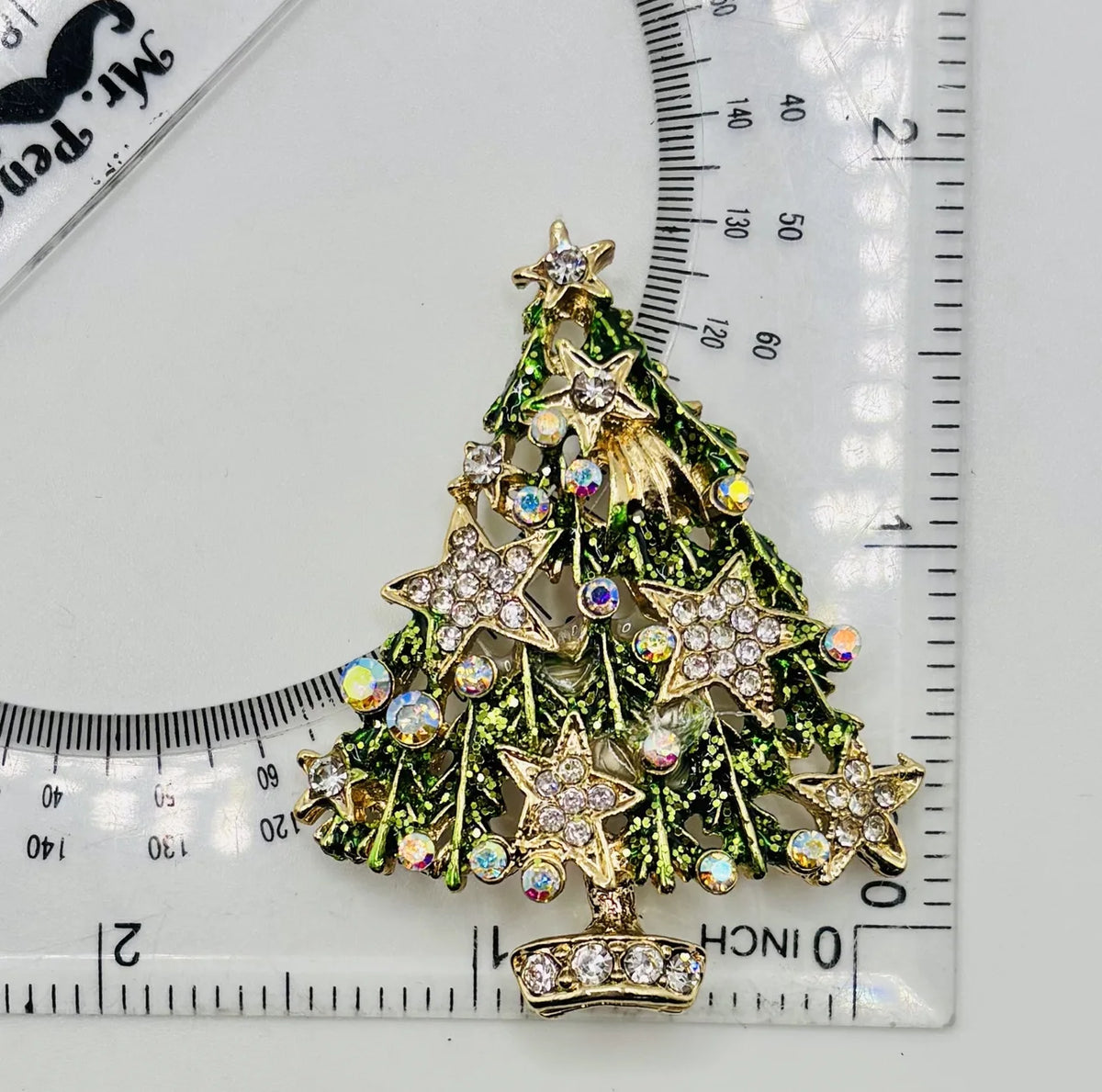 Green tree with crystal stars needle minder beside a ruler for scale