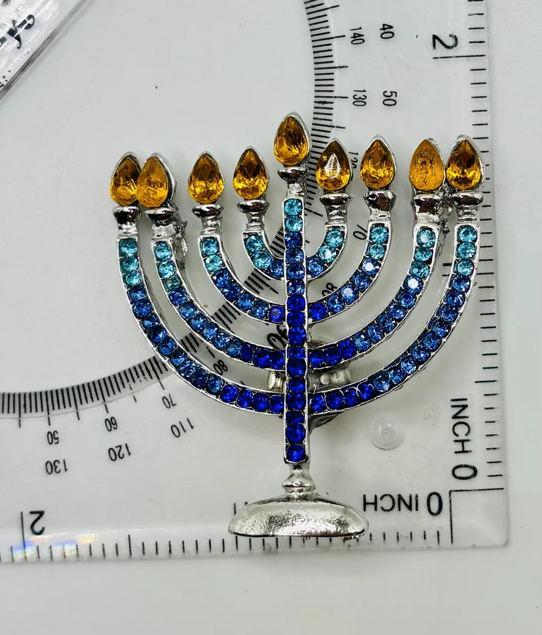 Crystal menorah needle minder beside a ruler for scale
