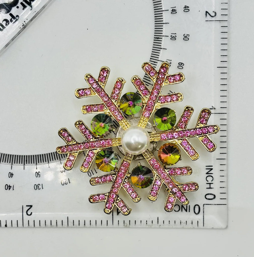 Pink snowflake needle minder beside a ruler for scale