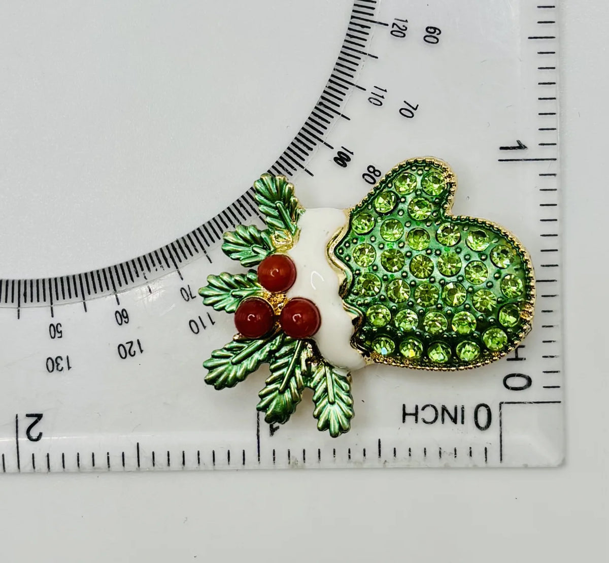 Green crystal mitten needle minder beside a ruler for scale