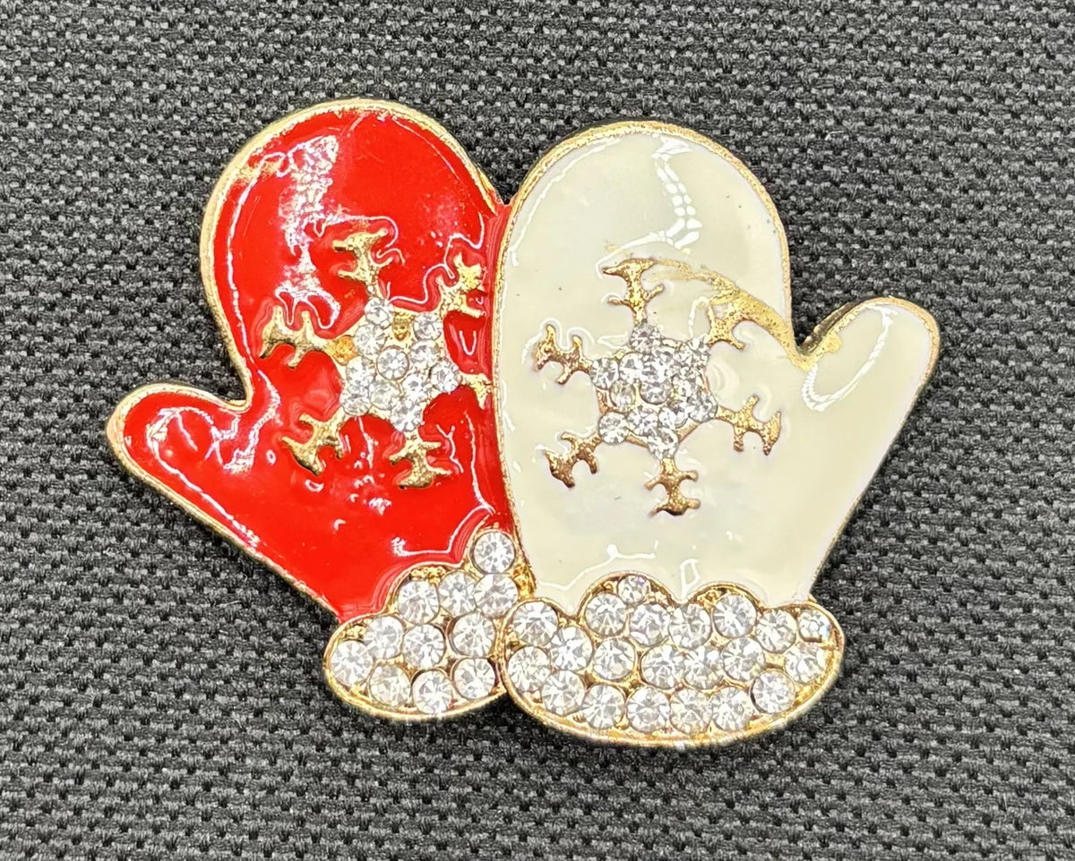 White and red enamel mittens needle minder on dark fabric