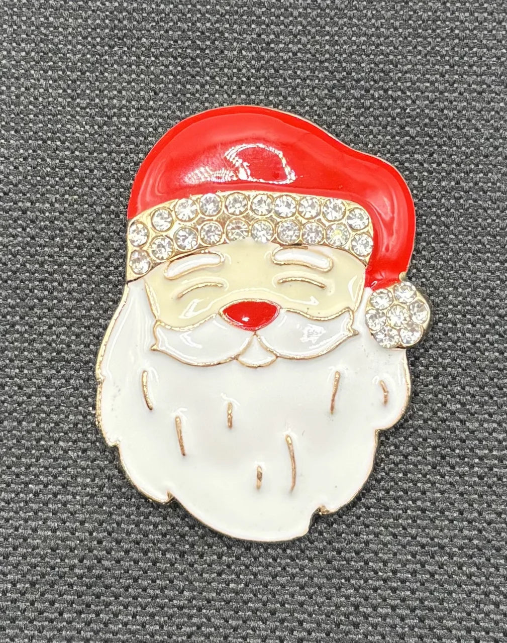 Enamel Santa face needle minder on dark fabric
