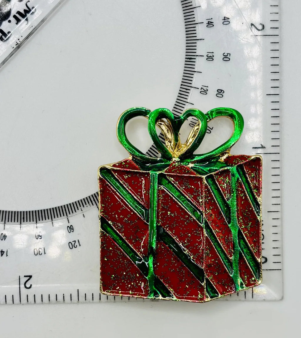 Red enamel present needle minder beside a ruler for scale