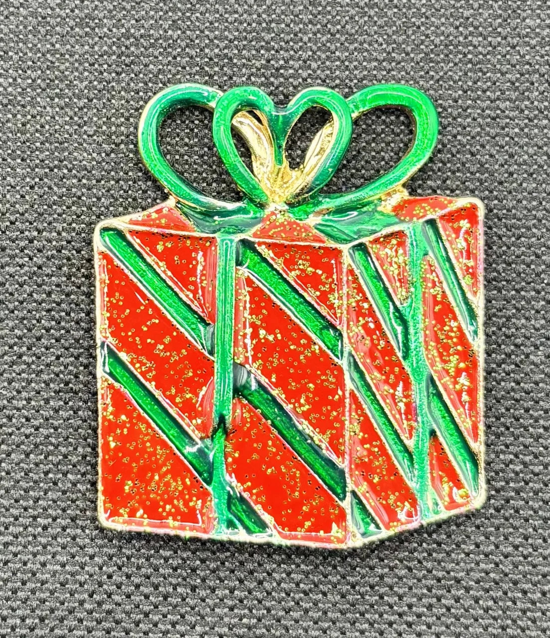 Red enamel present needle minder on dark fabric