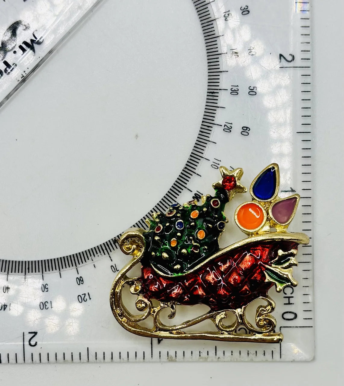 Enamel crystal sled needle minder beside a ruler for scale