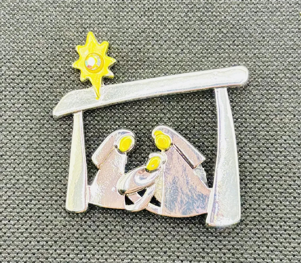 Silver and gold metal Holy Family needle minder on dark fabric