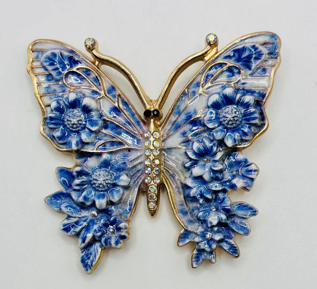 Blue enamel butterfly needle minder on a white background