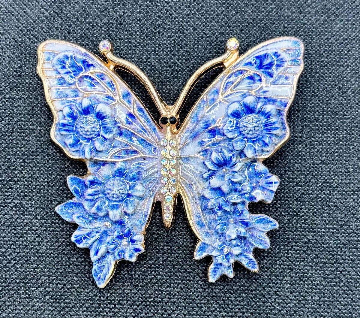 Blue enamel butterfly needle minder on dark fabric
