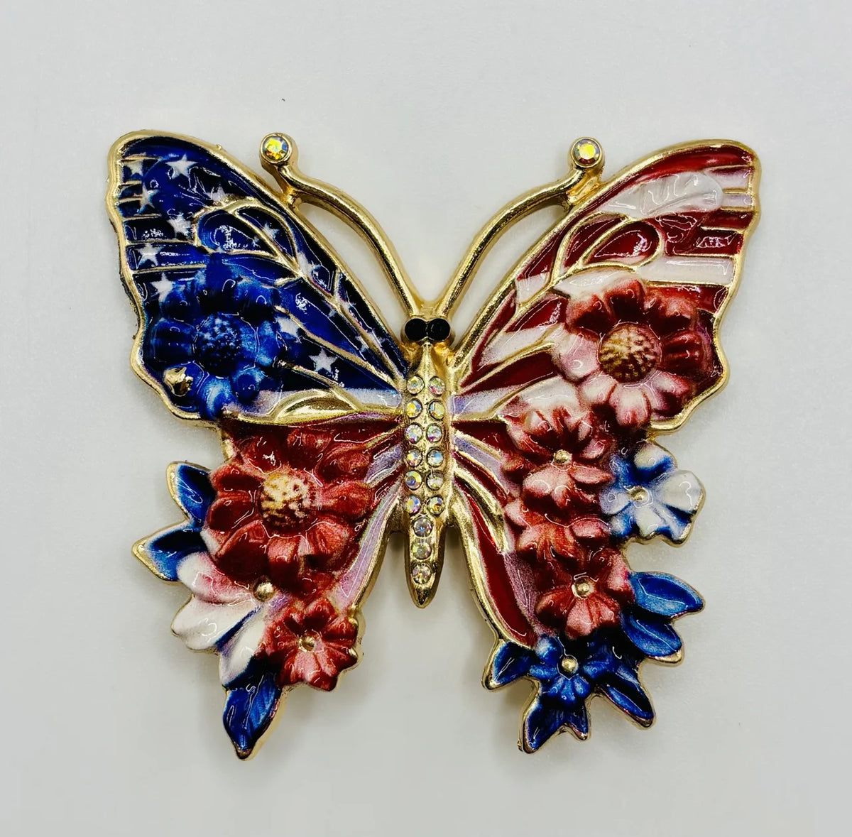 Red white and red white and blue enamel butterfly needle minder on a white background