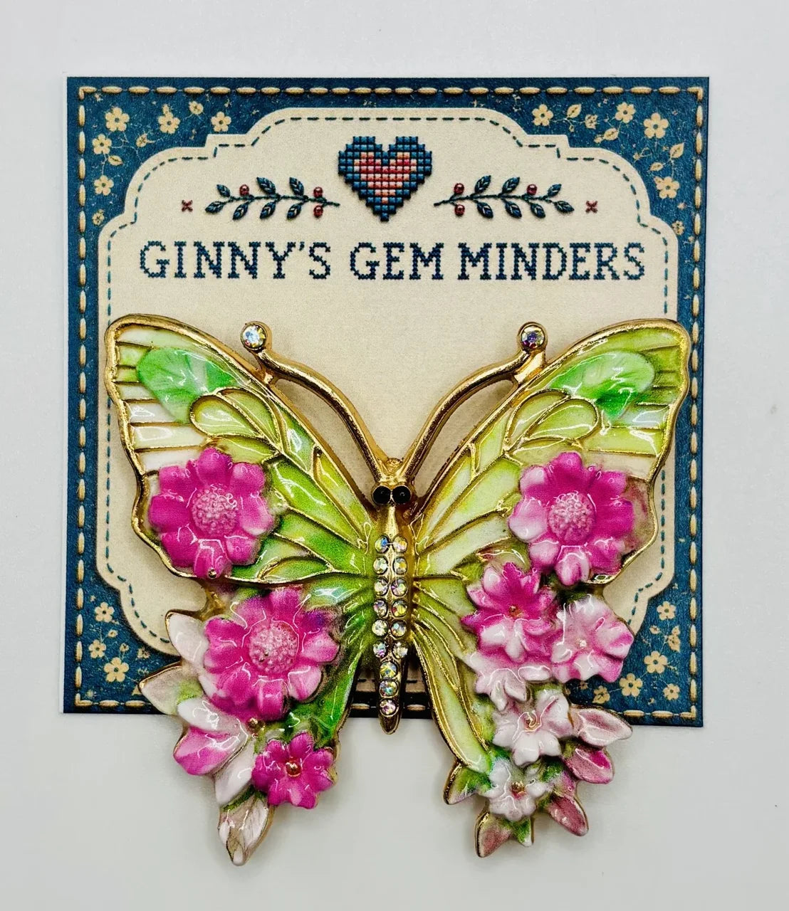 Pink and green enamel butterfly needle minder on Ginny’s Gem Minders display card