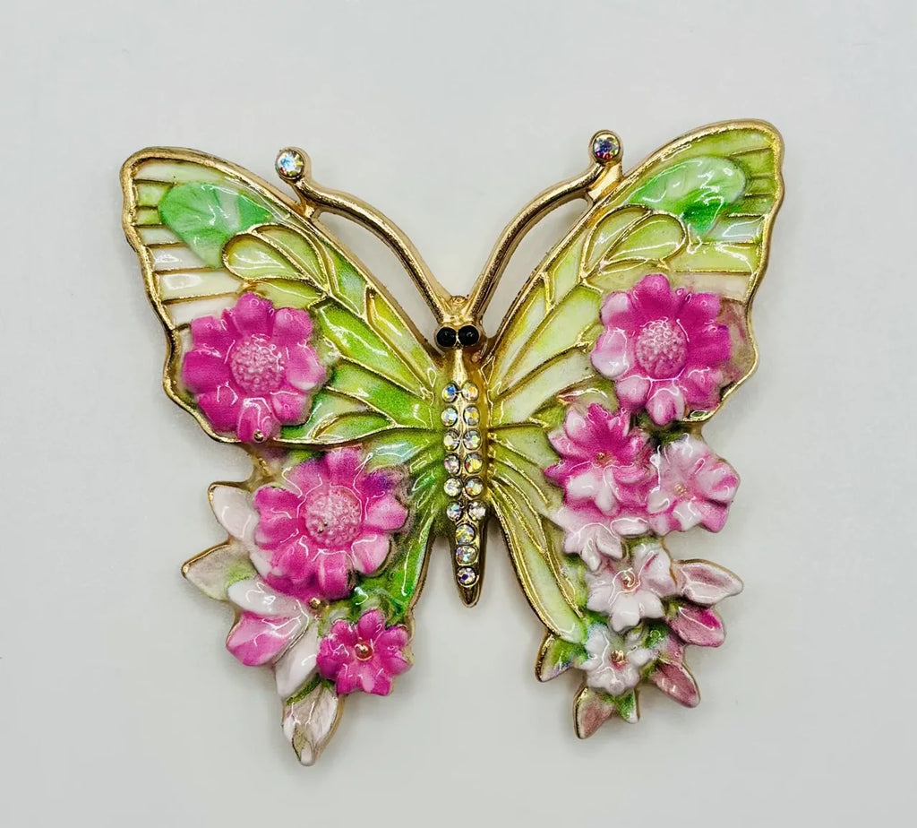 Pink and green enamel butterfly needle minder on a white background