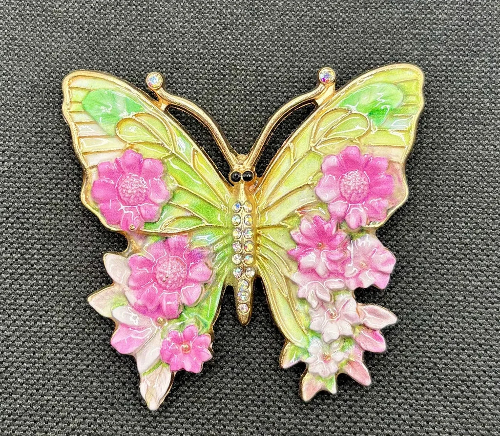 Pink and green enamel butterfly needle minder on dark fabric