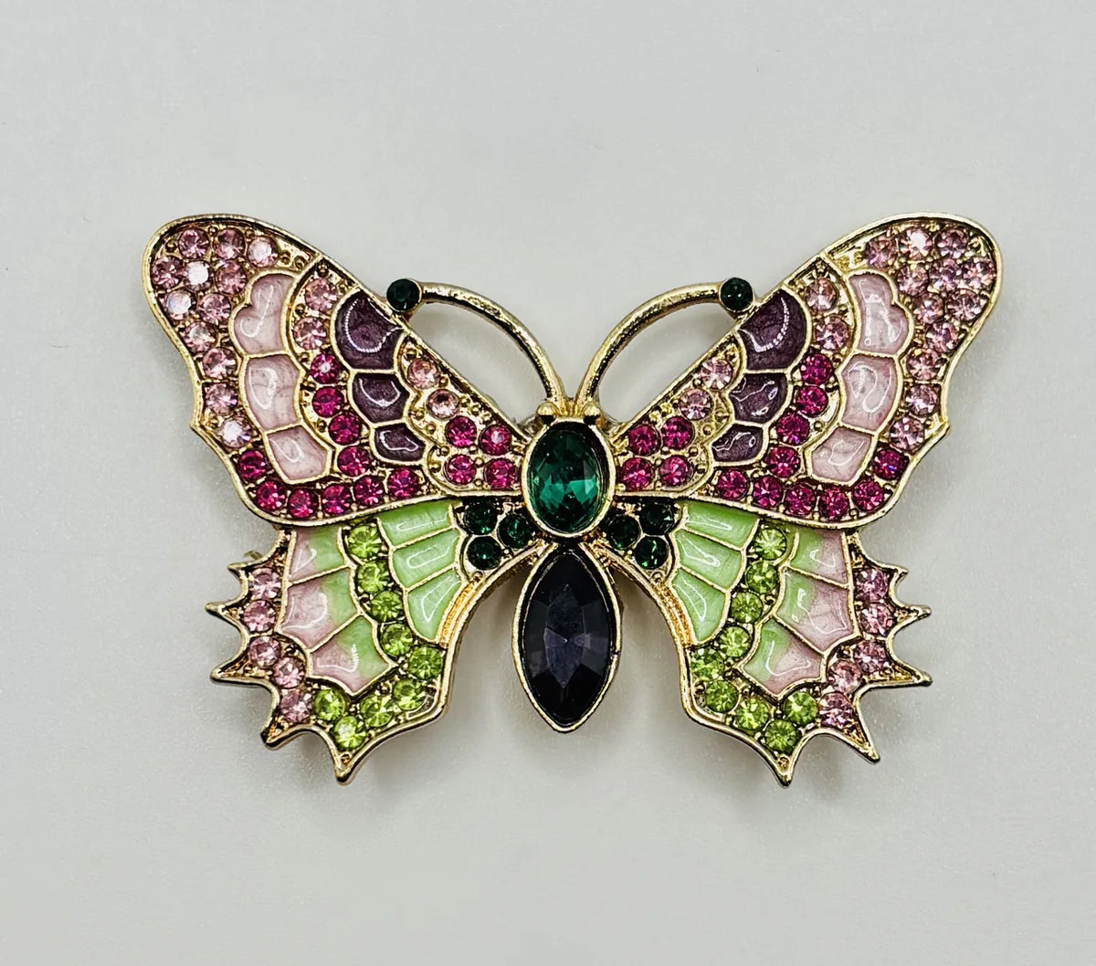 Red white and pink and green enamel crystal butterfly needle minder on a white background