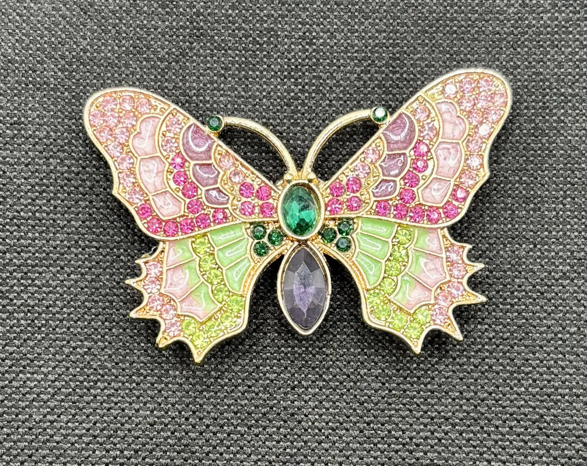Red white and pink and green enamel crystal butterfly needle minder on dark fabric