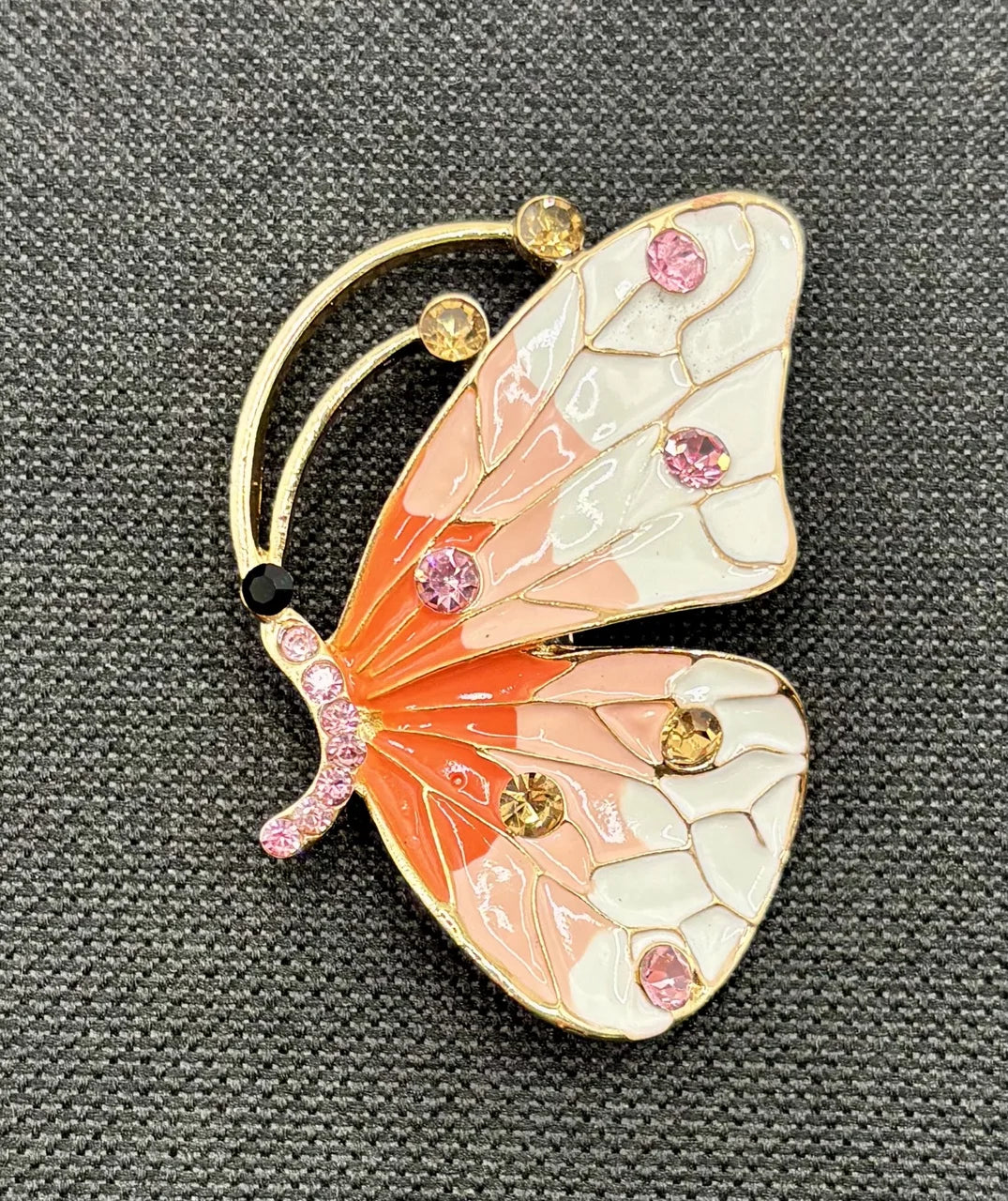 Red white and peach and white enamel and crystal butterfly needle minder on dark fabric