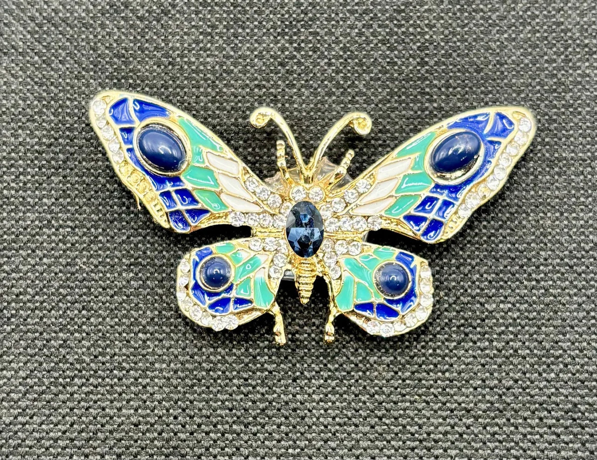 Red white and small blue green and white enamel crystal butterfly needle minder on dark fabric