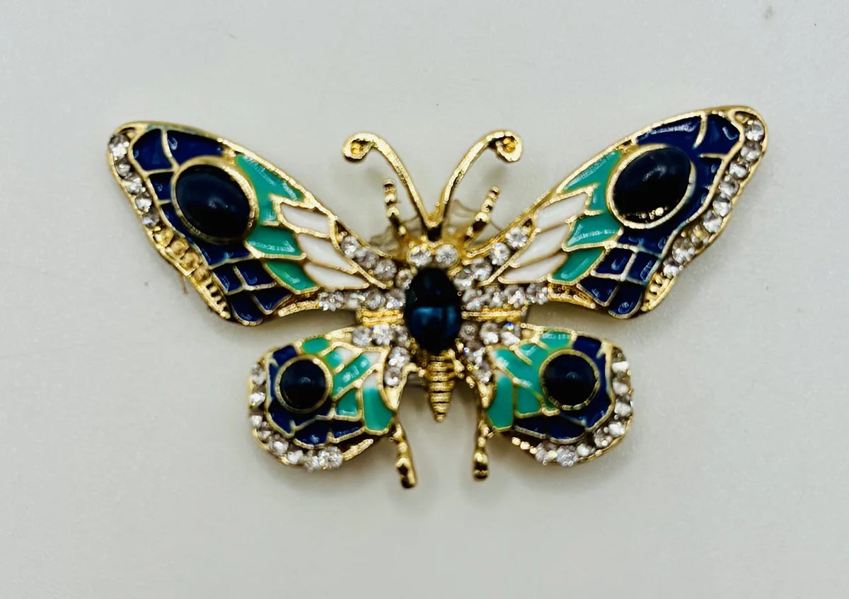 Red white and small blue green and white enamel crystal butterfly needle minder on a white background